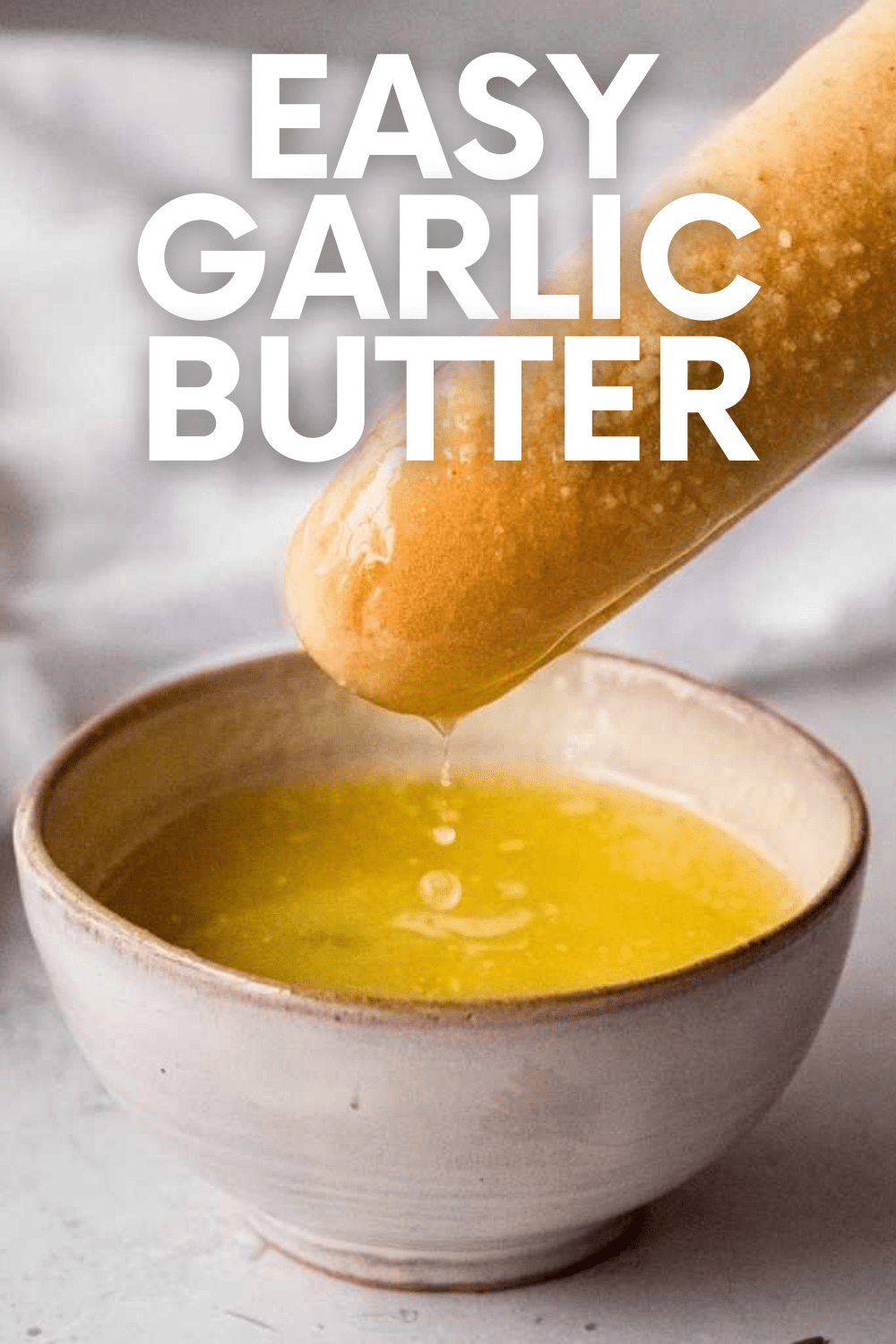 A soft breadstick dips into a bowl of melted garlic butter sauce. A text overlay reads "Easy Garlic Butter"