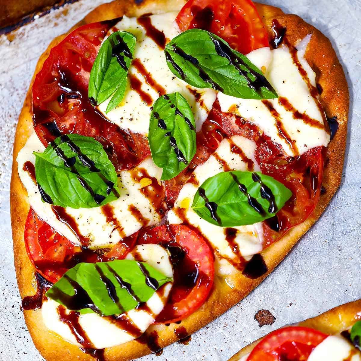Square photo of caprese pizza on naan bread.