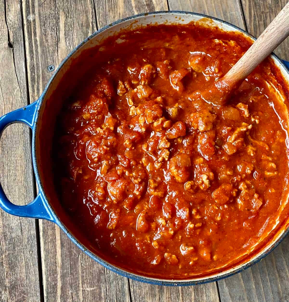 turkey bolognese in a pot with large spoon.